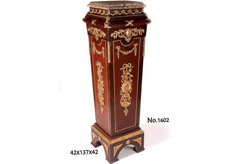 French Empire style ormolu-mounted veneer inlaid vase stand / pedestal, marble topped, and ornamented with gilt ormolu mounts of scrolling hanging foliage medallions, ribbons, trophies and musical instruments, the central part is inlaid with Bubinga veneer surrounded with ormolu beaded encadrement and veneered outside with palisander veneer, raised on a shaped rectangular base ornamented with ormolu beaded encadrement frieze and gilt-ormolu rosettes